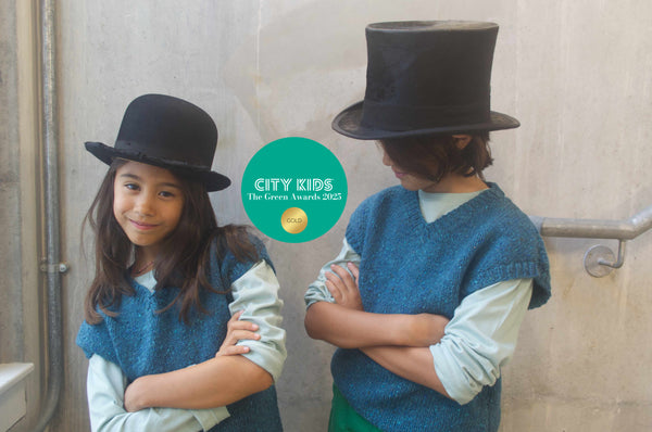 Two children wearing vintage hats one bowler hats the other top hat. Wearing Kin and Cloth collection handcrafted pieces.